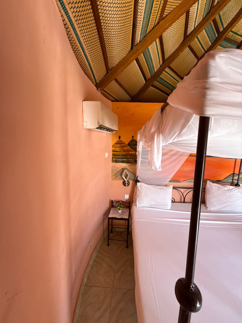 Chambre climatisée avec lit à baldaquin à l'Hôtel Les Cristaux Roses au Lac Rose