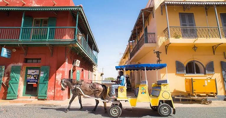 Calèche devant les maisons coloniales colorées du centre historique de Saint-Louis du Sénégal