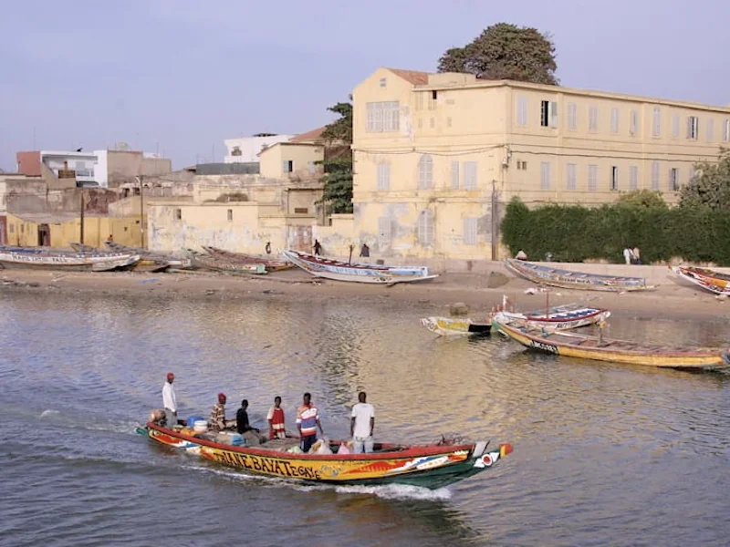 Pirogue de pêche naviguant sur le fleuve Sénégal devant les quais historiques de Saint-Louis