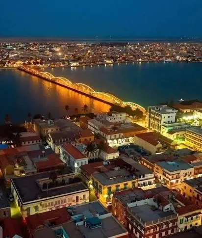 Vue nocturne de Saint-Louis et des lumières du pont Faidherbe au-dessus du fleuve Sénégal