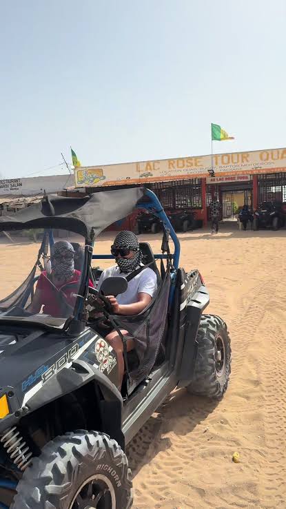Visiteurs à bord d’un buggy devant une base d’activités du Lac Rose