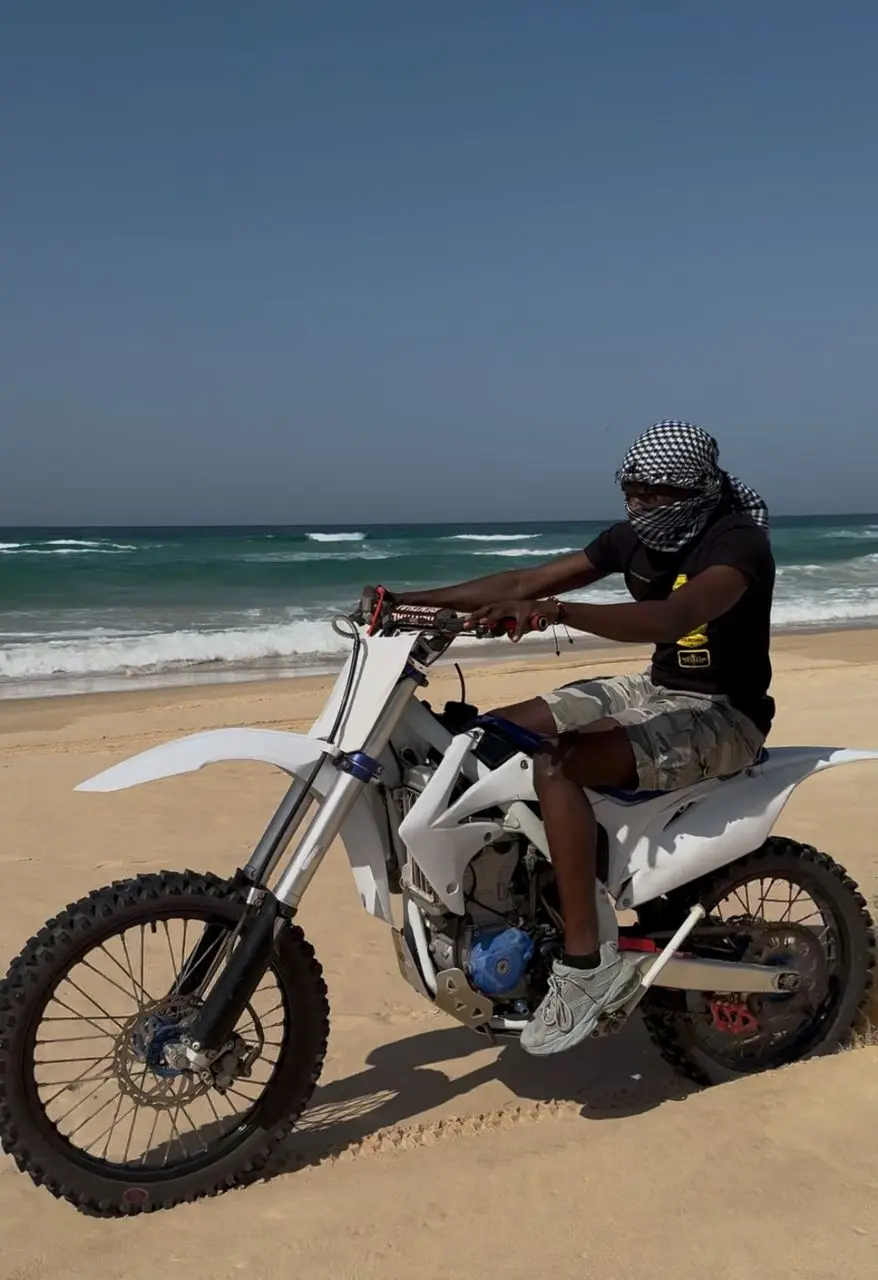 Pilote sur une moto-cross blanche sur la plage près du Lac Rose