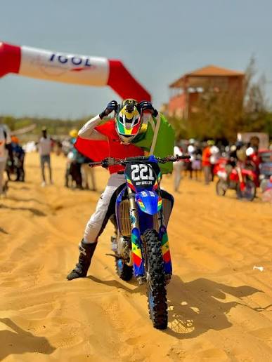 Pilote de moto-cross prêt au départ sur une piste de sable au Sénégal