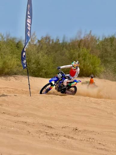 Moto-cross bleue en virage sur une piste de sable