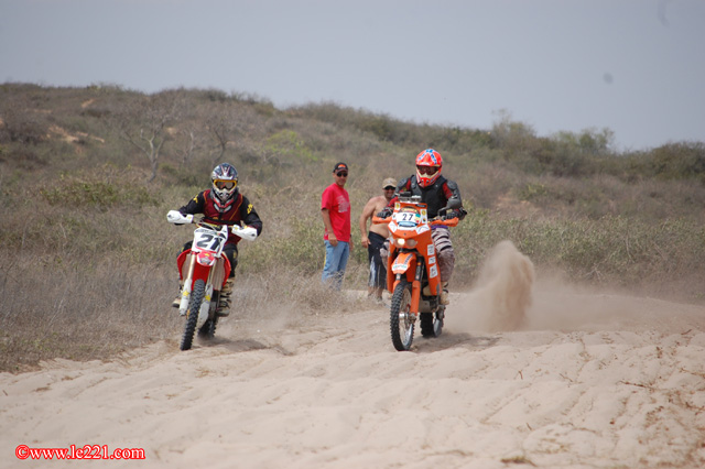 Deux pilotes de moto-cross avançant sur une piste sablonneuse