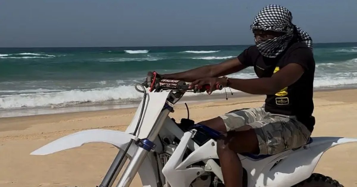 Pilote sur une moto-cross blanche sur la plage près du Lac Rose