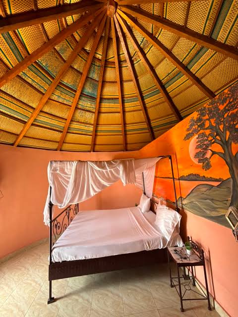 Chambre ventilée au toit traditionnel et lit sous moustiquaire au Lac Rose